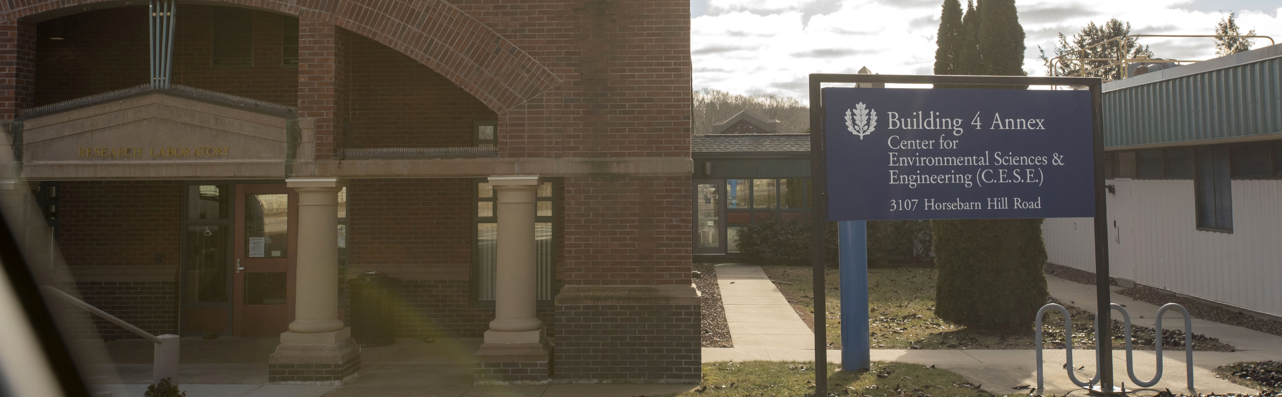 The brick exterior of the Center for Environmental Sciences & Engineering facility with a sign in front that says, "Building 4 Annex, Center for Environmental Sciences & Engineering (CESE), 3107 Horsebarn Hill Road"